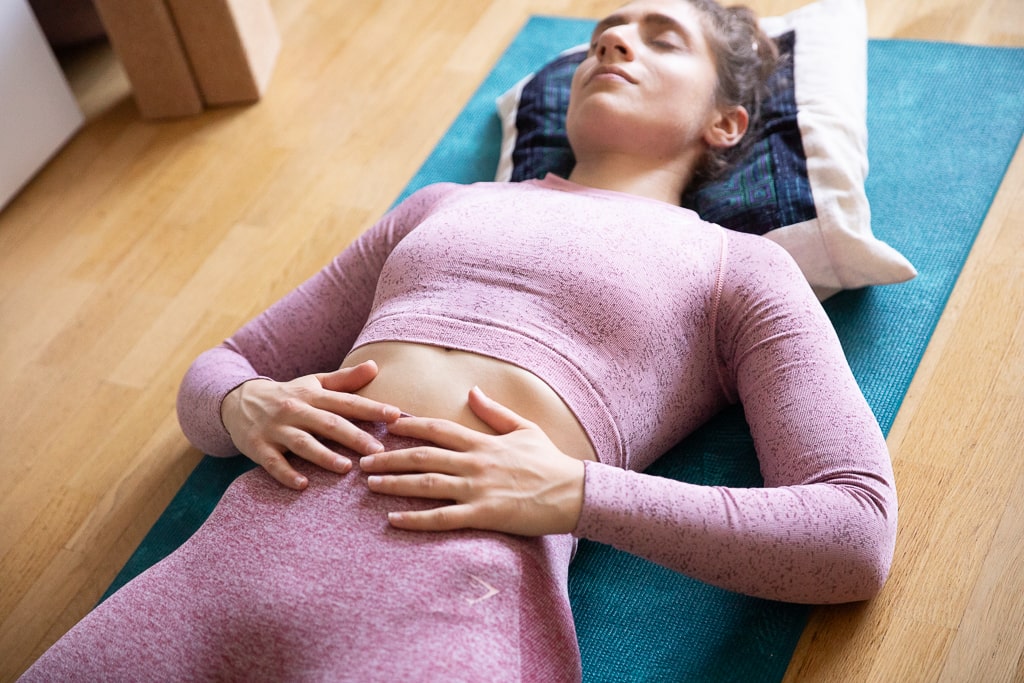 Une jeune femme termine sa séance de sport par un temps de méditation et d'acceptation de soi