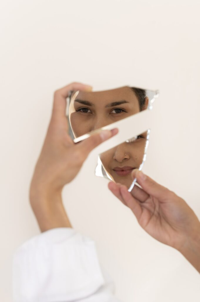 Une jeune femme observe toutes ses facettes dans un miroir pour s'accepter telle qu'elle est.